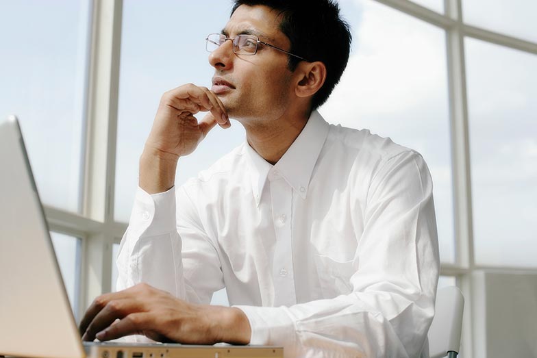 man with laptop and hand under chin looking thoughtful