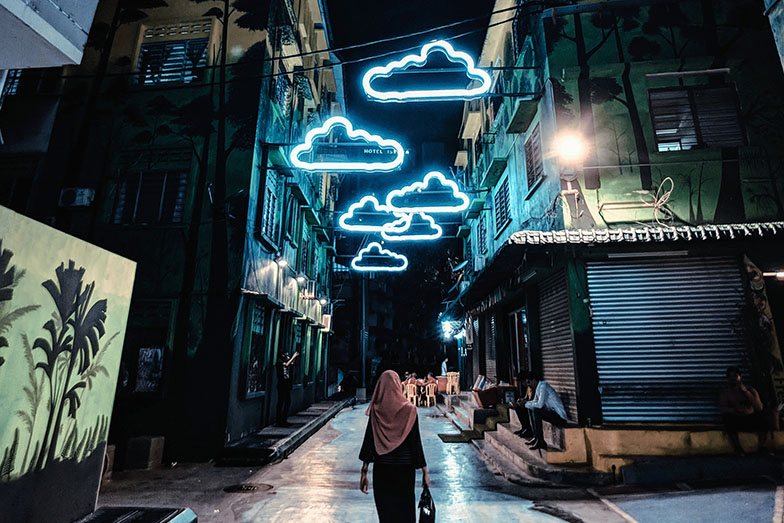 Person walking down a street with cloud shaped street lights above