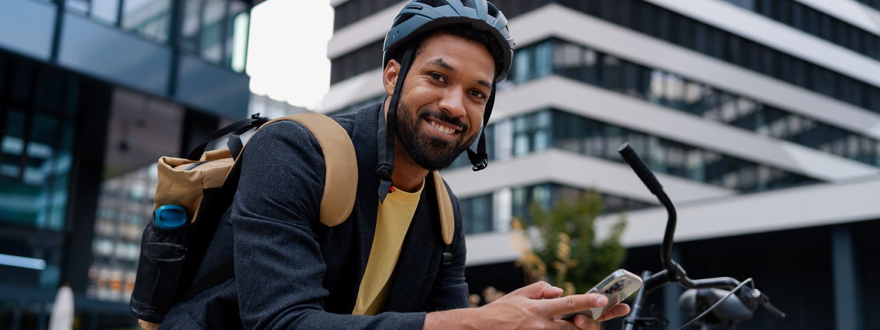 Person smiling with bike in urban setting