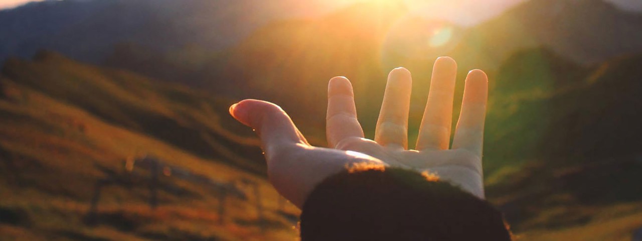 open hand with sunrise in background