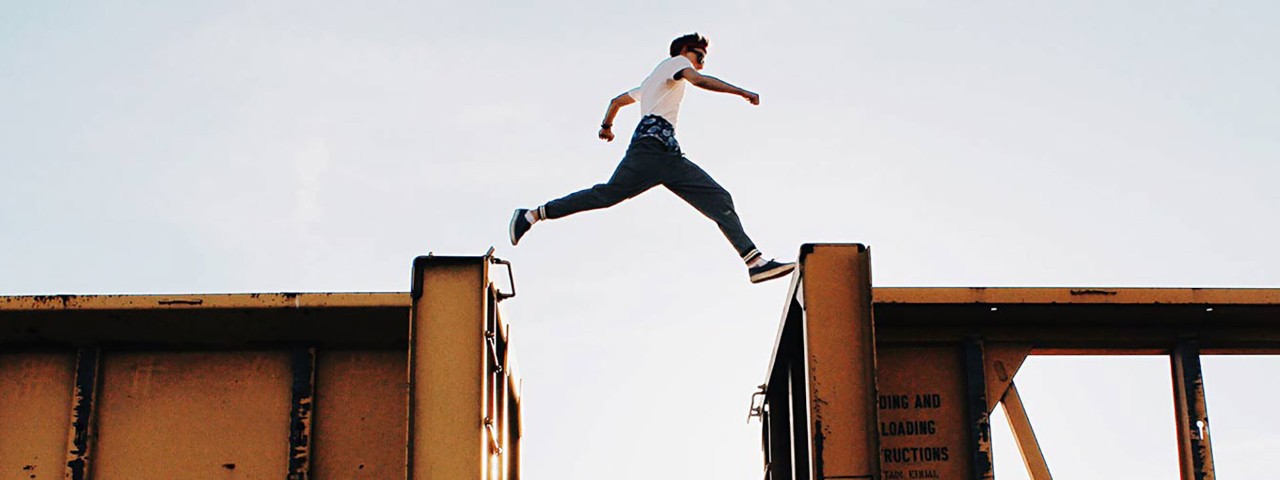 Person jumping between two cargo train carriages
