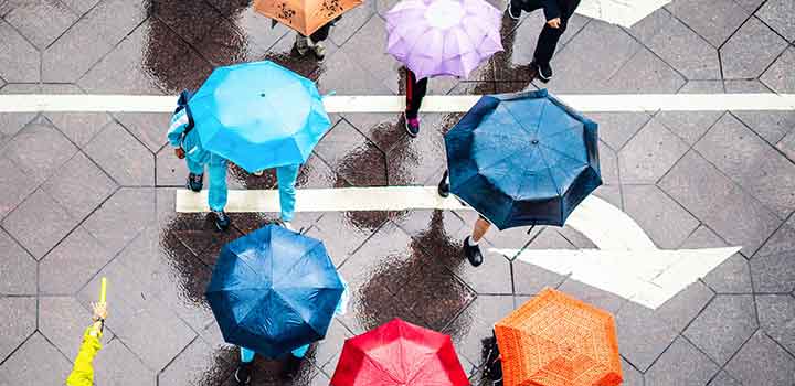 Image from above of people navigating a busy street under colourful umbrellas on a wet day Image from above of people navigating a busy street under colourful umbrellas on a wet day