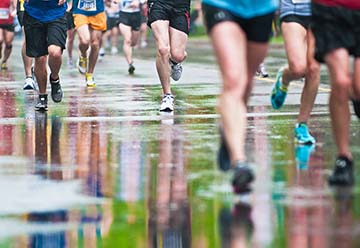 Colorful outfits of marathon runners are reflected on rain-soaked asphalt during Ottawa International Marathon.