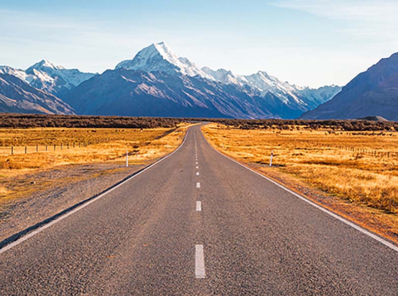 straight road with snow-capped mountains in the distance