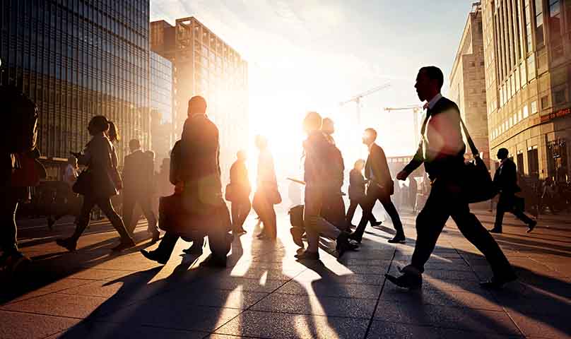 commuters walking to work silhouetted against the rising sun