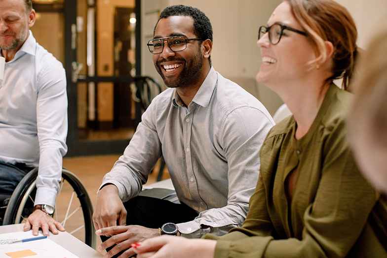 Three people sat at a low table smiling