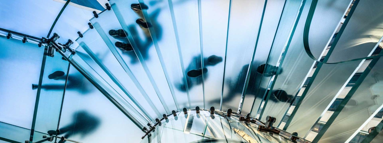 view from beneath a glass staircase of people's feet
